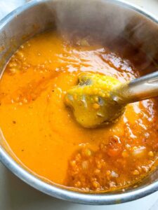 Recipe step of blending finished creamy red lentil soup with hand blender