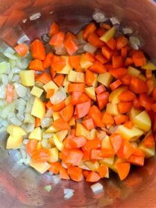 diced potatoes and carrots added to the Sautéed onions in the pot