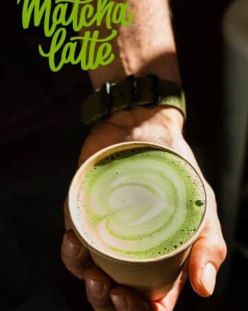 hand holding a cup of creamy oat milk matcha latte